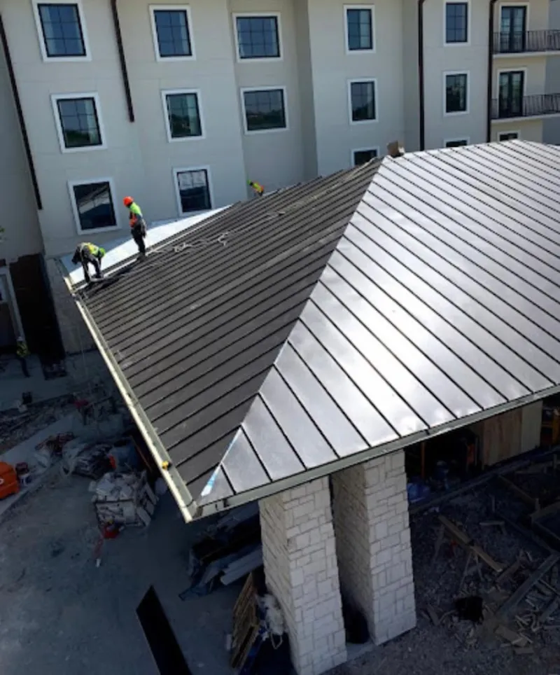 Crew installing standing seam metal roof panels on a commercial project in Chain Lake